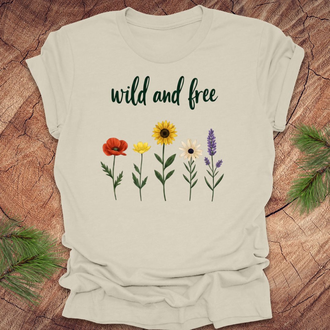 Beige t-shirt with floral designs and 'wild and free' text on a wooden surface