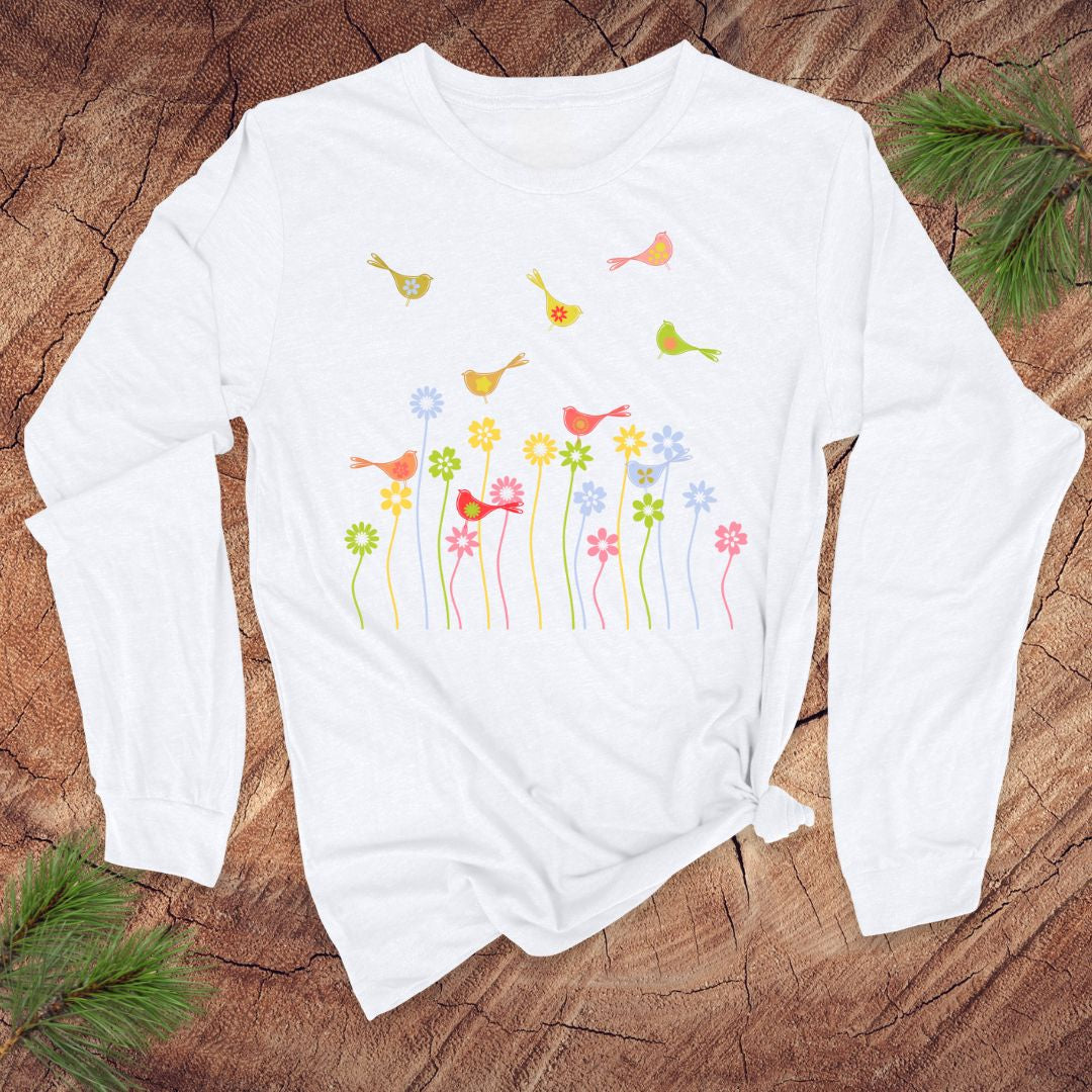 White long-sleeve shirt with colorful bird and flower design on a wooden surface