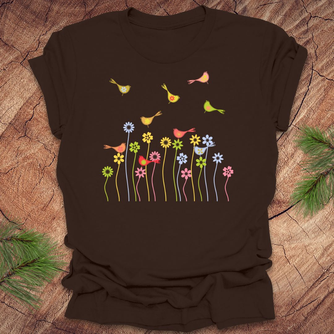 Brown t-shirt with colorful bird and flower design on a wooden surface