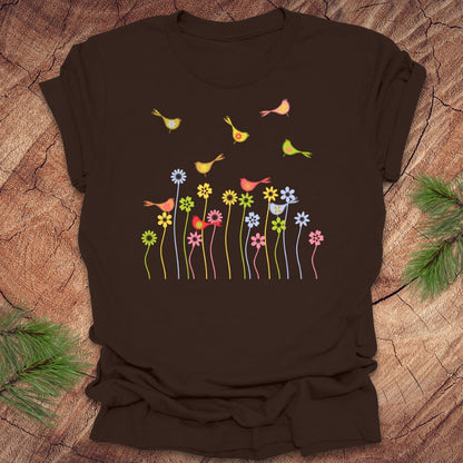 Brown t-shirt with colorful bird and flower design on a wooden surface