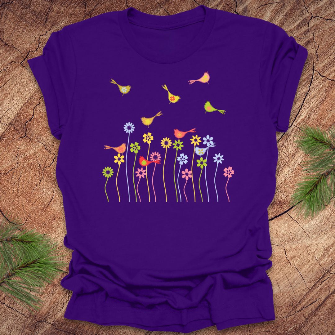 Purple t-shirt with colorful bird and flower design on a wooden surface