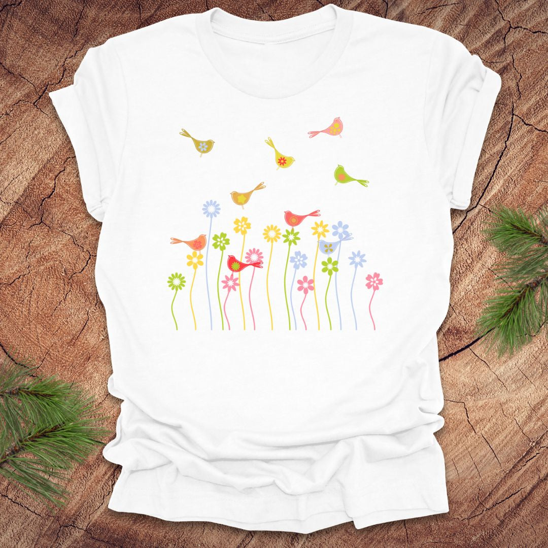White t-shirt with colorful bird and flower design on a wooden surface