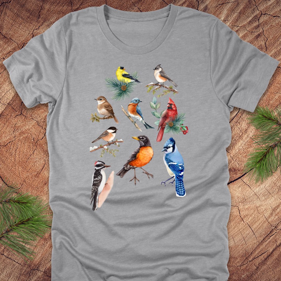 Gray t-shirt with colorful bird illustrations on a wooden surface