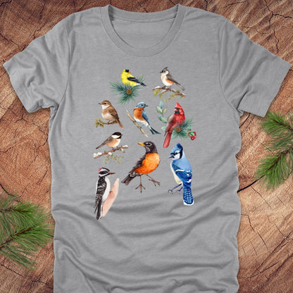 Gray t-shirt with colorful bird illustrations on a wooden surface