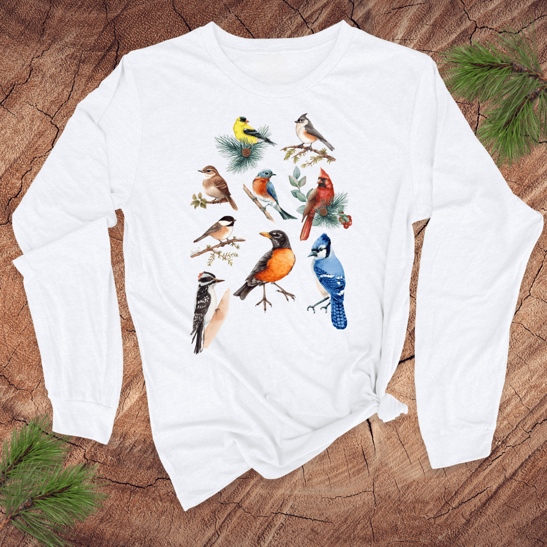 White long-sleeve shirt with colorful bird illustrations on a wooden surface
