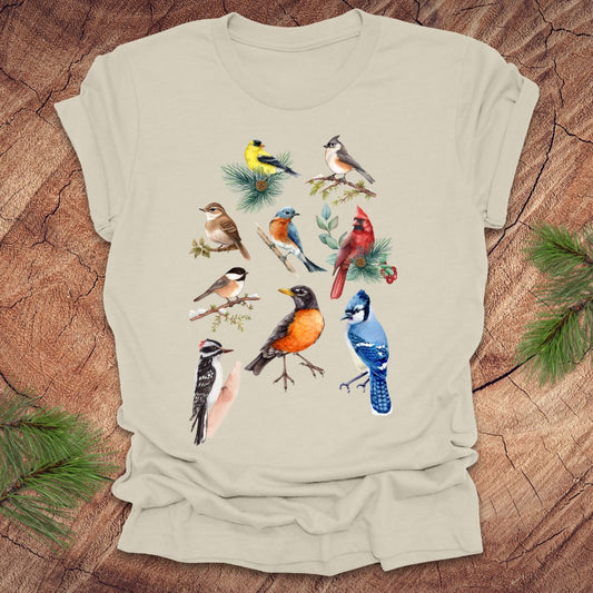 Beige t-shirt with colorful bird illustrations on a wooden surface