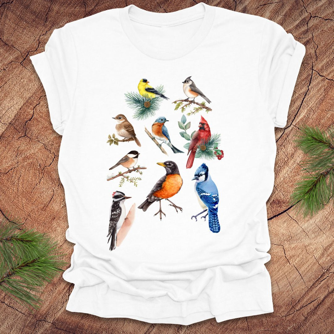 White t-shirt with colorful bird illustrations on a wooden surface