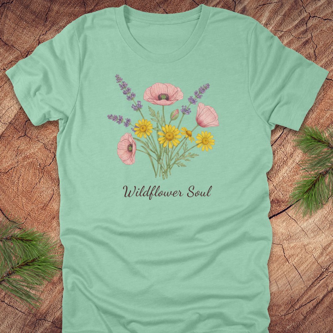 Light green t-shirt with floral design and 'Wildflower Soul' text on a wooden surface.