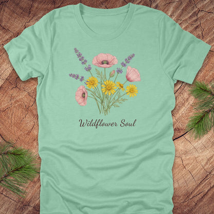 Light green t-shirt with floral design and 'Wildflower Soul' text on a wooden surface.