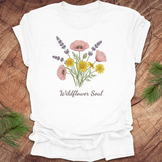 White t-shirt with floral design and 'Wildflower Soul' text on a wooden surface.