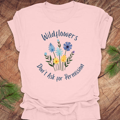 Pink t-shirt with floral design and text on a wooden surface
