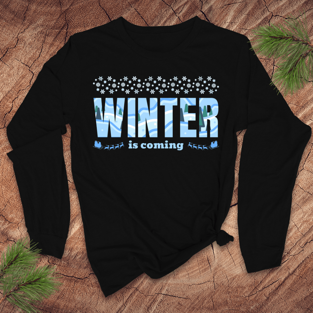 Black sweatshirt with 'Winter is coming' text on a wooden surface with pine branches.