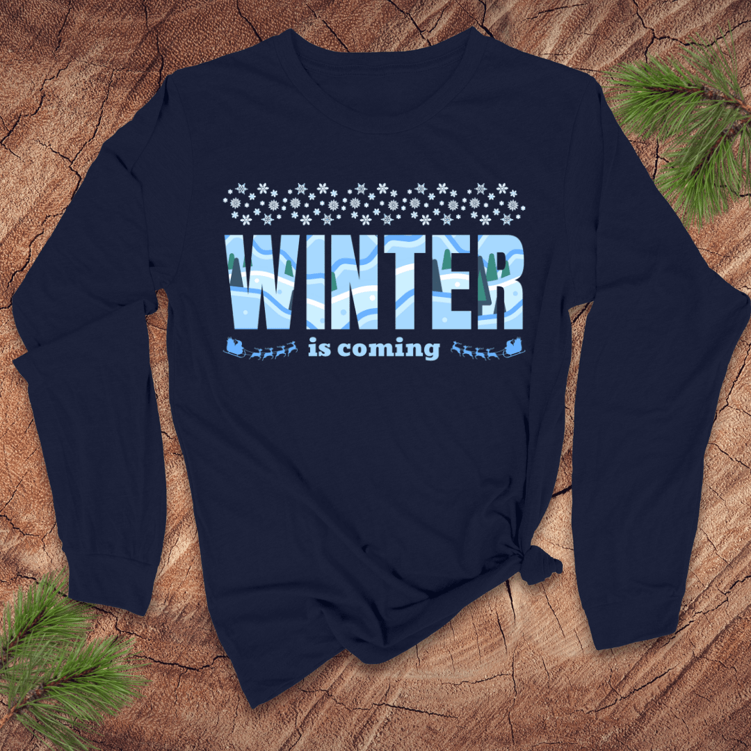 Navy blue long-sleeve shirt with 'Winter is coming' text on a wooden surface with pine branches.