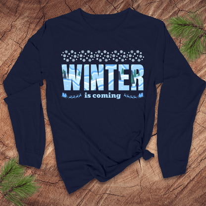 Navy blue long-sleeve shirt with 'Winter is coming' text on a wooden surface with pine branches.
