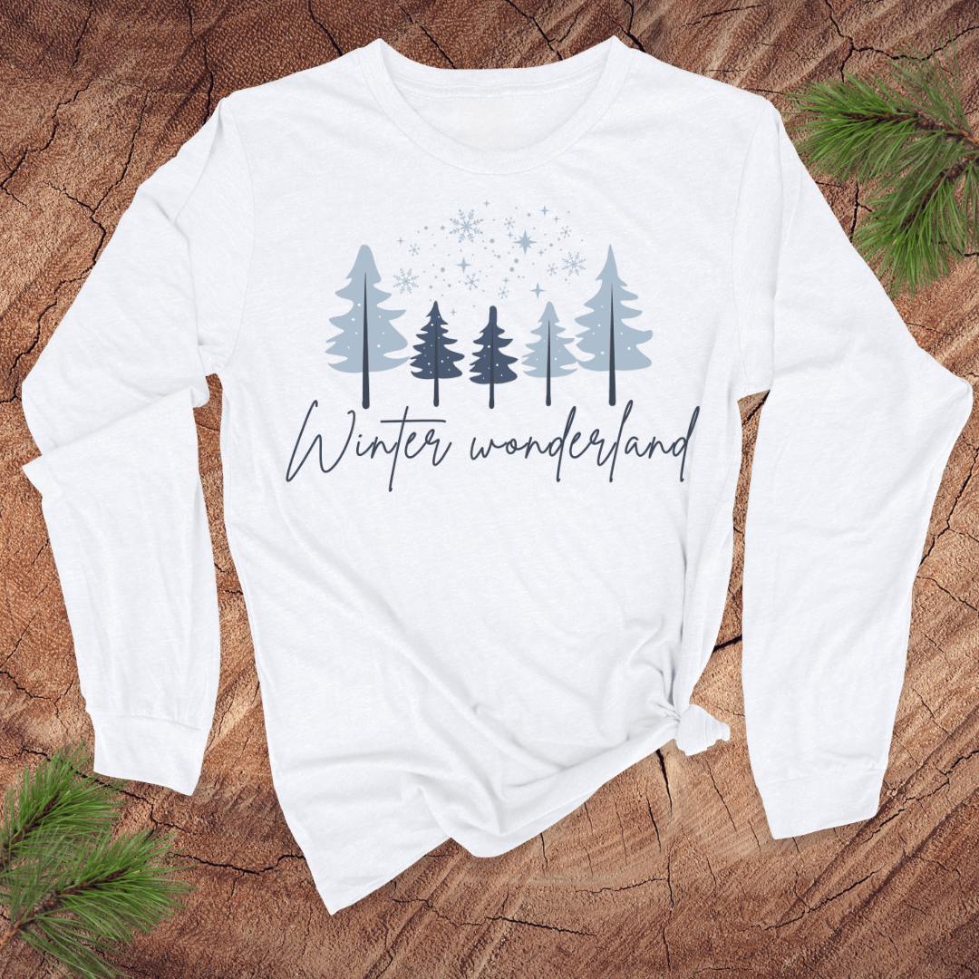 White long-sleeve shirt with 'Winter wonderland' text and tree design on a wooden surface.