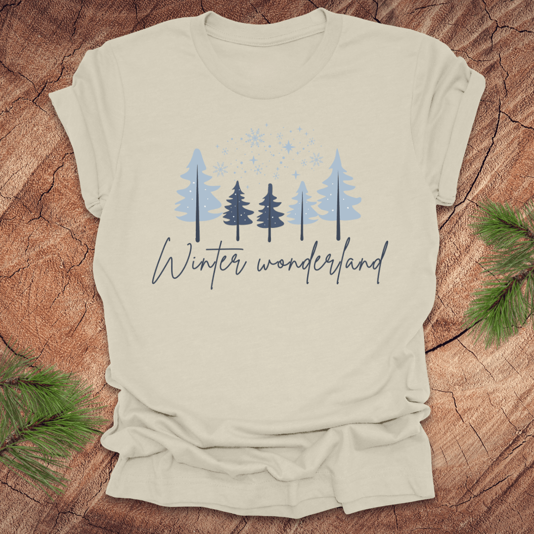 Beige t-shirt with 'Winter wonderland' text and trees with snow design on a wooden surface