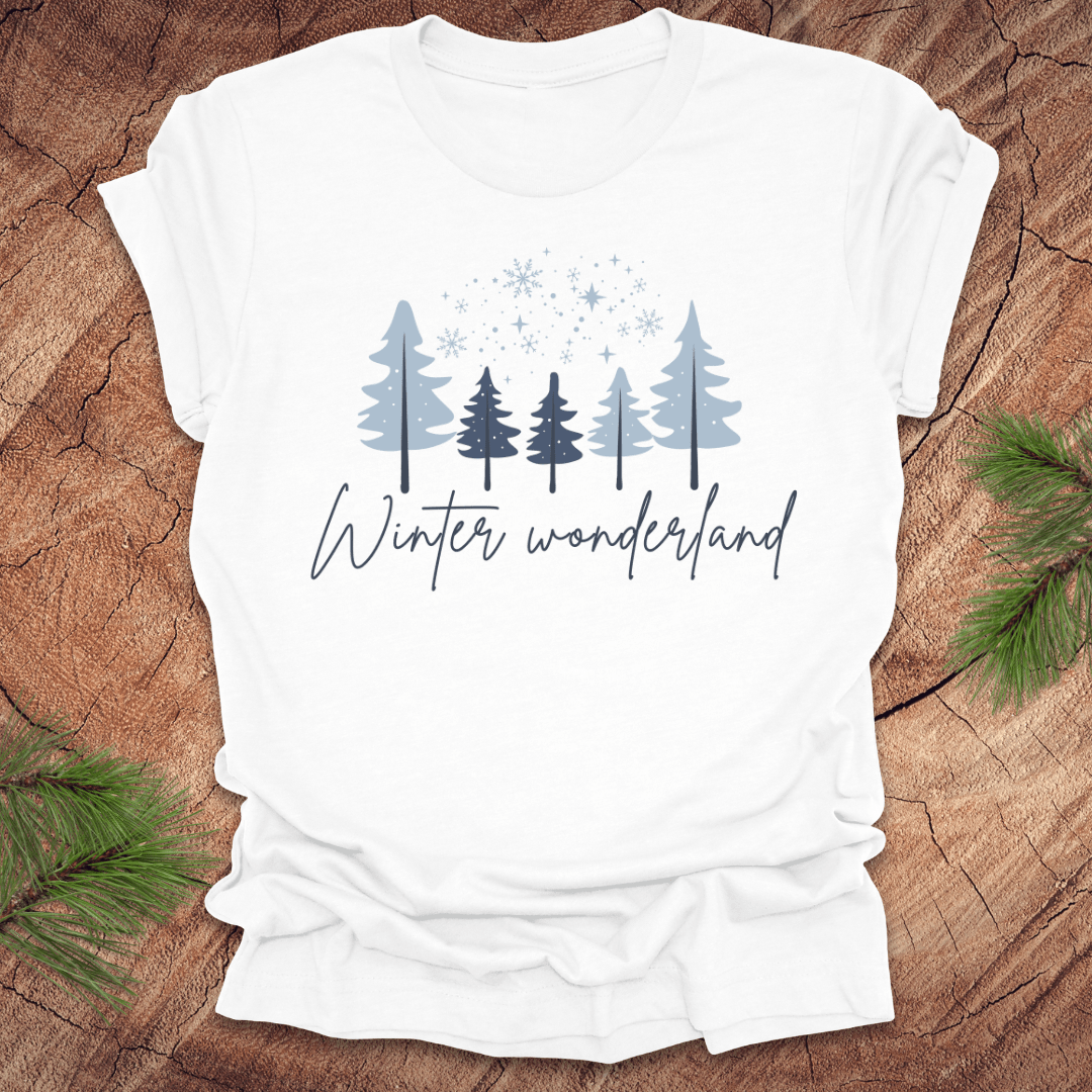 White t-shirt with 'Winter wonderland' text and trees with snow design on a wooden surface