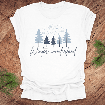 White t-shirt with 'Winter wonderland' text and trees with snow design on a wooden surface