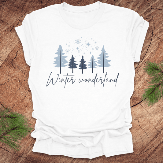 White t-shirt with 'Winter wonderland' text and trees with snow design on a wooden surface