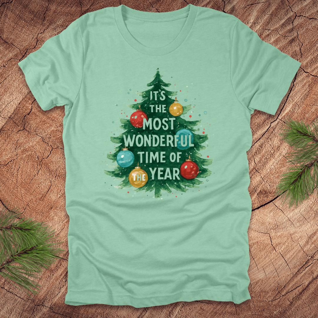 Mint green t-shirt with Christmas tree design and text on a wooden surface.