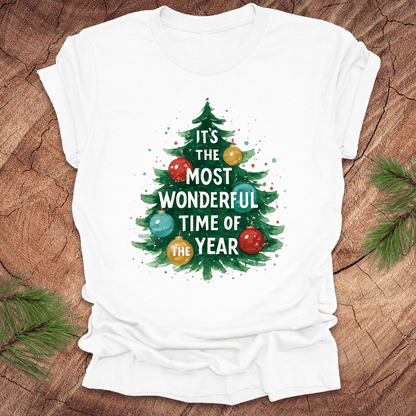 White t-shirt with Christmas tree design and text on a wooden surface