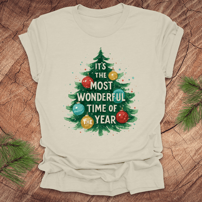 Beige t-shirt with Christmas tree design and text on a wooden surface