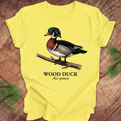 Yellow t-shirt with a wood duck graphic and text on a wooden surface.