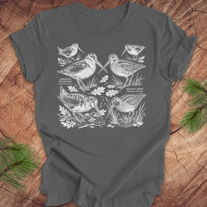 Gray t-shirt with woodcock and snipe illustrations on a wooden surface