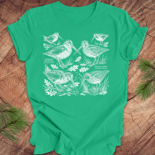 Green t-shirt with woodcock and snipe illustrations on a wooden surface