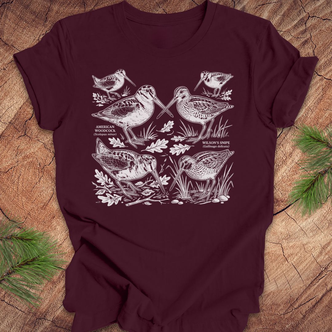 Maroon t-shirt with woodcock and snipe illustrations on a wooden surface