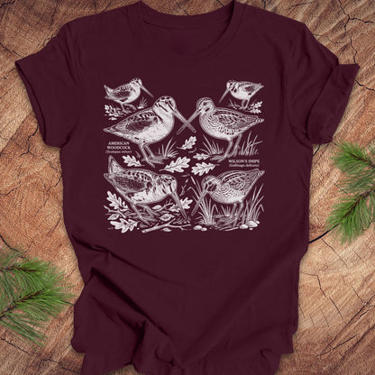 Maroon t-shirt with woodcock and snipe illustrations on a wooden surface