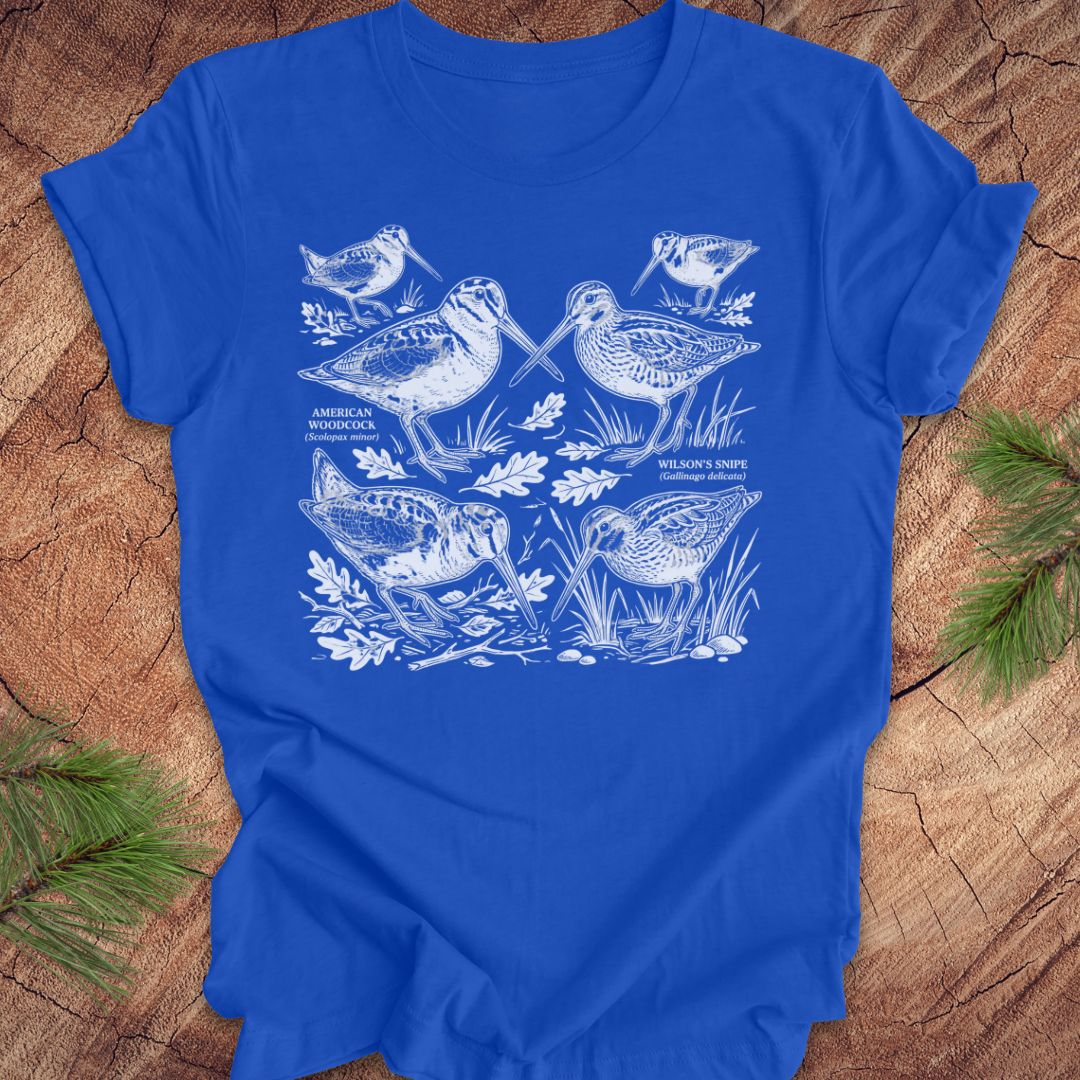 Blue t-shirt with woodcock and snipe illustrations on a wooden surface