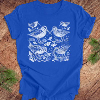 Blue t-shirt with woodcock and snipe illustrations on a wooden surface