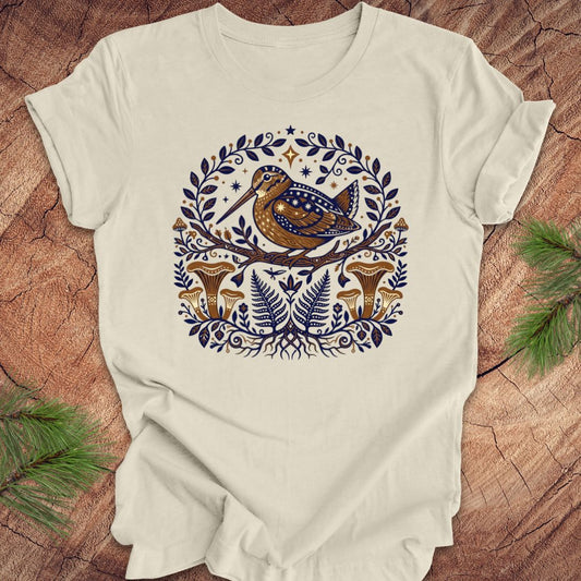 Beige t-shirt with a woodcock and mushroom design on a wooden surface