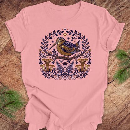 Pink t-shirt with a woodcock and mushroom design on a wooden surface