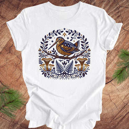 White t-shirt with a woodcock and mushroom design on a wooden surface