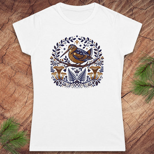White t-shirt with a woodcock bird and nature-themed design on a wooden surface.