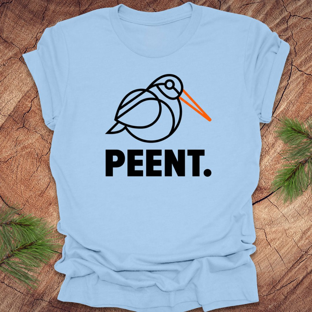Light blue t-shirt with a woodcock graphic and 'PEENT.' text on a wooden surface.