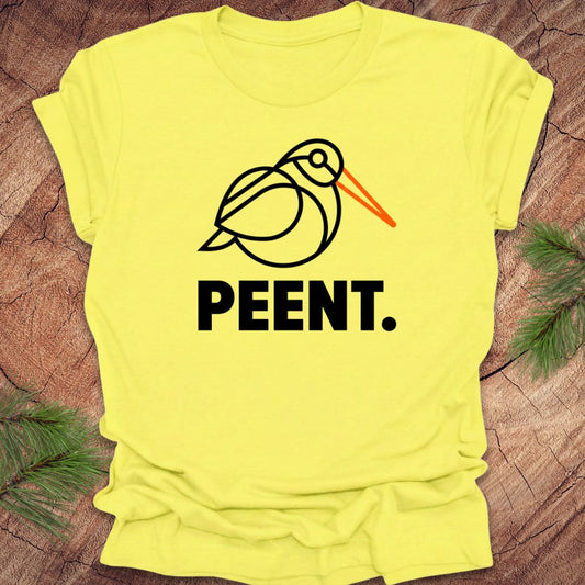 Yellow t-shirt with a woodcock graphic and 'PEENT.' text on a wooden surface.