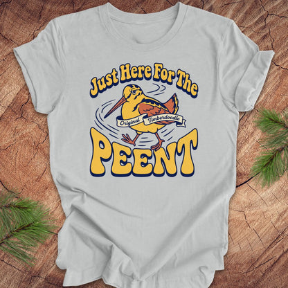 Gray t-shirt with 'Just Here For The Peent' woodcock graphic on a wooden surface