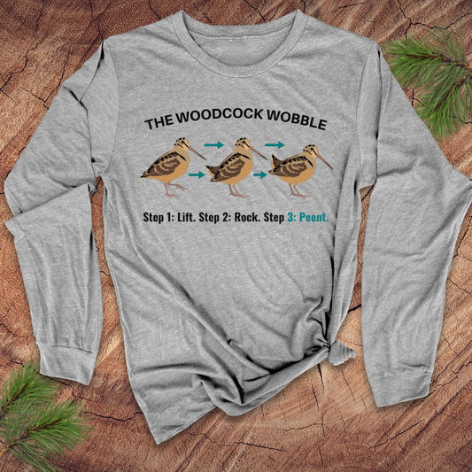 Gray long-sleeve shirt with woodcock wobble graphic on a wooden surface