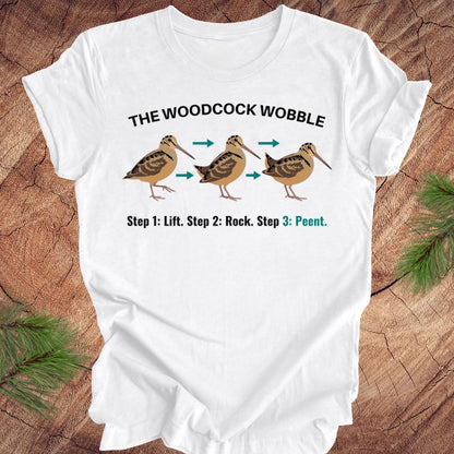 White t-shirt with woodcock wobble graphic on a wooden surface