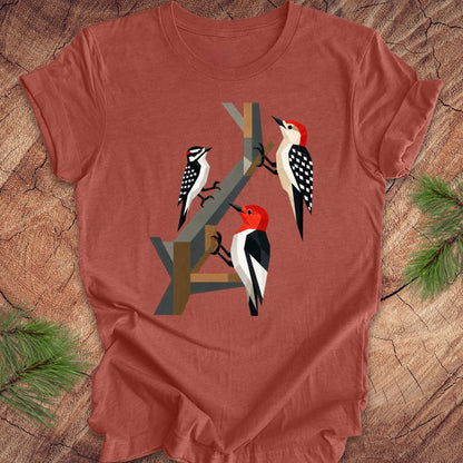 Red t-shirt with woodpecker design on a wooden surface