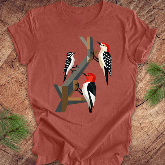 Red t-shirt with woodpecker design on a wooden surface