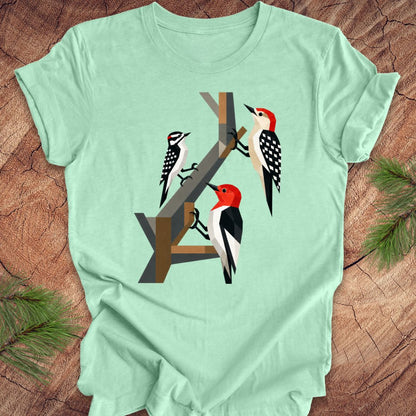 Mint green t-shirt with woodpecker design on a wooden surface