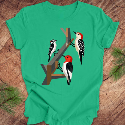 Green t-shirt with woodpecker design on a wooden surface