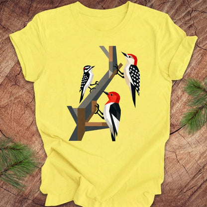 Yellow t-shirt with woodpecker design on a wooden surface
