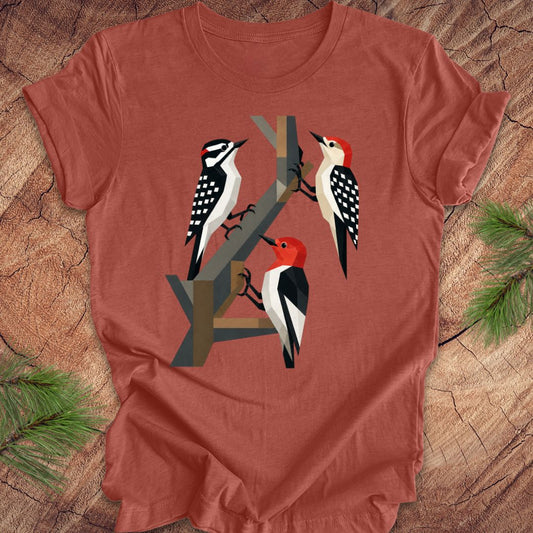 Clay colored t-shirt with woodpecker design on a wooden surface