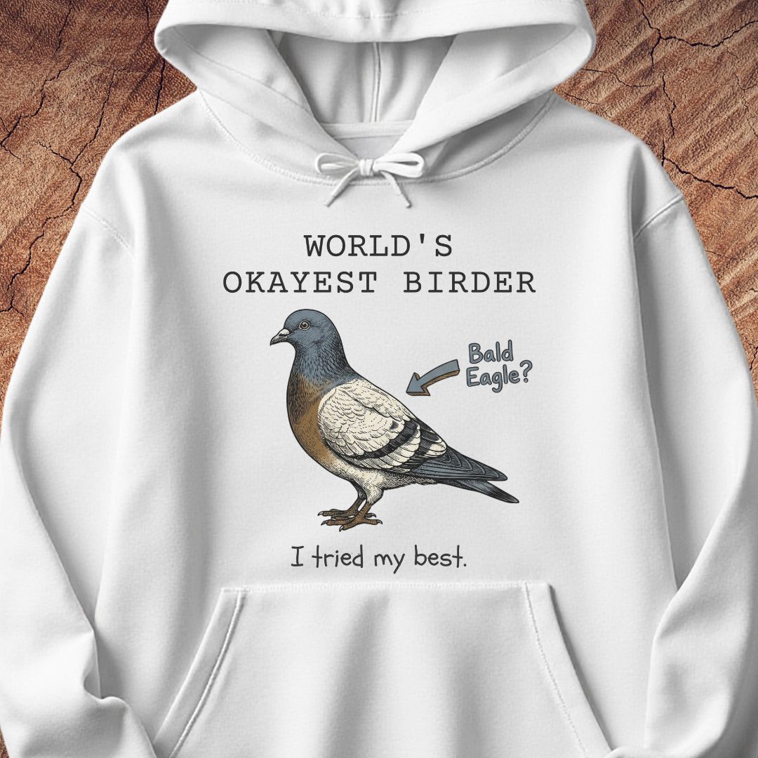 A white pullover hoodie with a graphic print of a pigeon and the text 'WORLD'S OKAYEST BIRDER' and 'I tried my best.' with an arrow pointing to the bird labeled 'Bald Eagle?'.