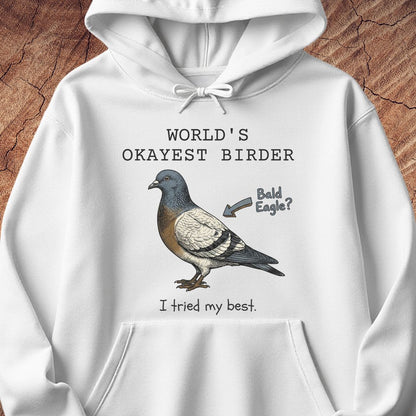A white pullover hoodie with a graphic print of a pigeon and the text 'WORLD'S OKAYEST BIRDER' and 'I tried my best.' with an arrow pointing to the bird labeled 'Bald Eagle?'.